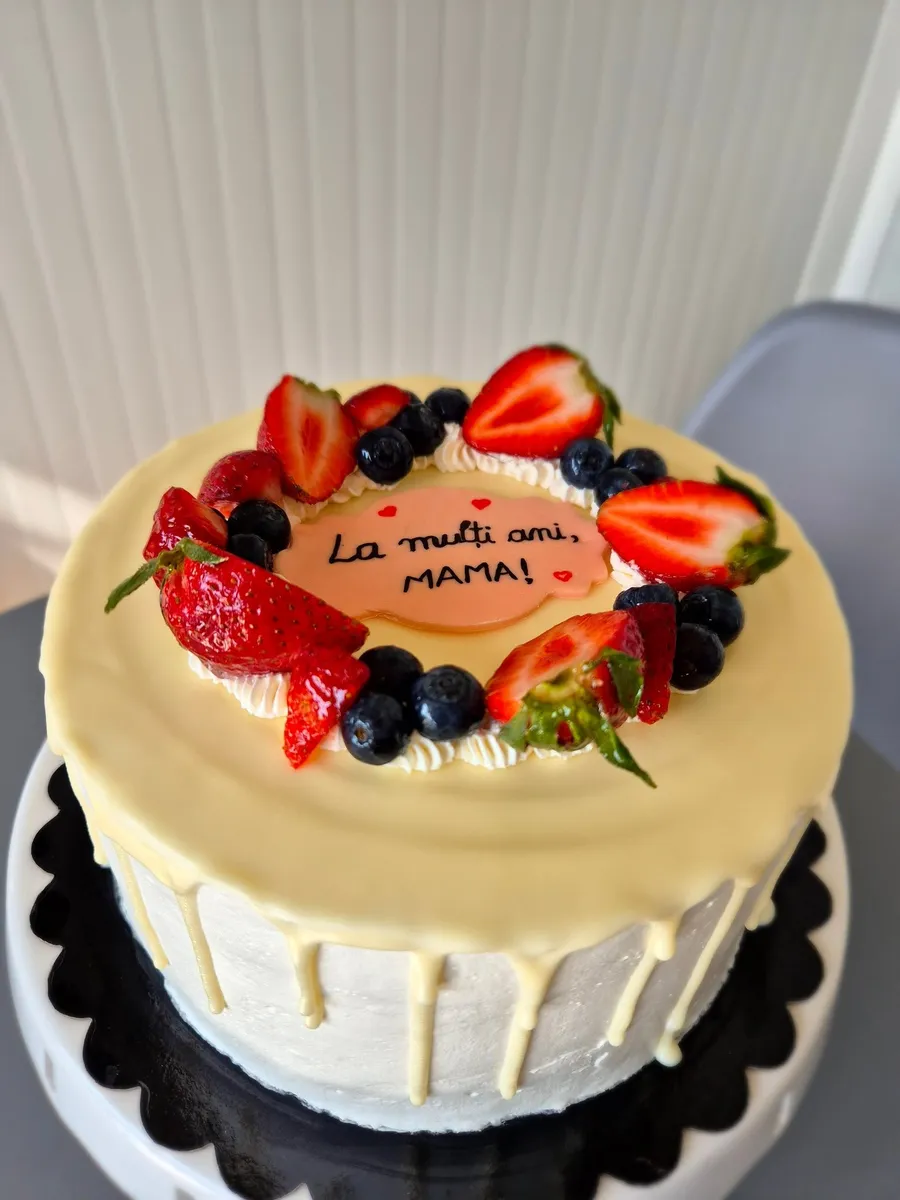 Tort cu drip de ciocolată albă și coroană de căpșuni și afine, făcut la Fancy Cakes
